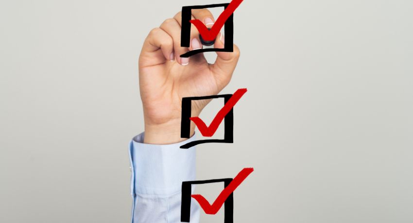Pessoa marcando caixas de checklist com caneta vermelha, simbolizando organização e planejamento de abertura de loja.